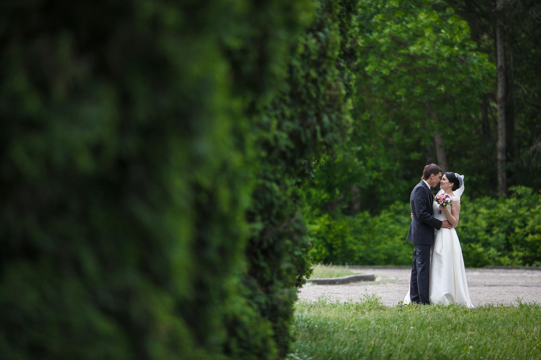 Para młoda obejmuje się w zielonym parku podczas pleneru ślubnego