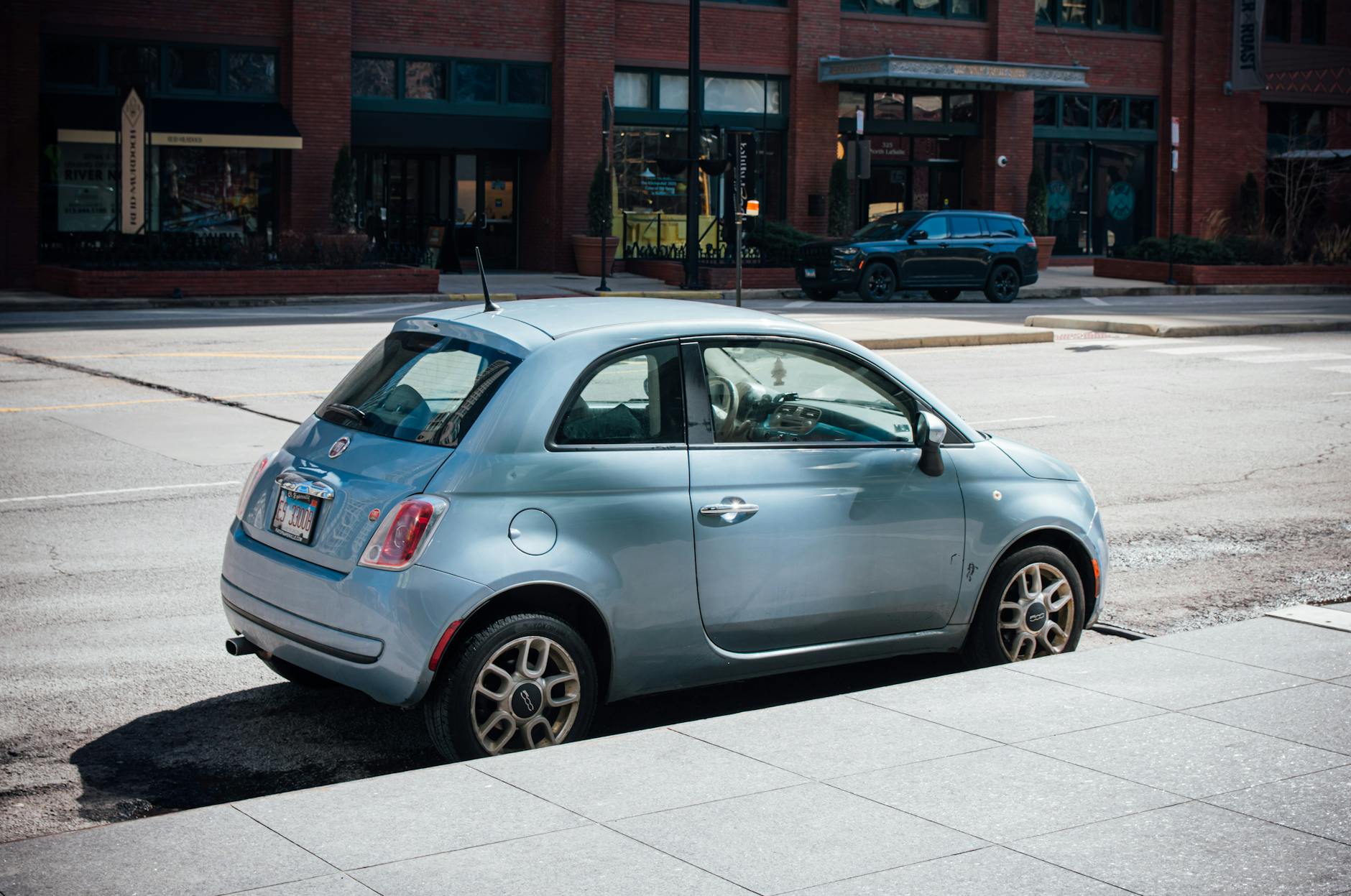 Niebieski Fiat 500 zaparkowany przy ceglanej kamienicy w mieście