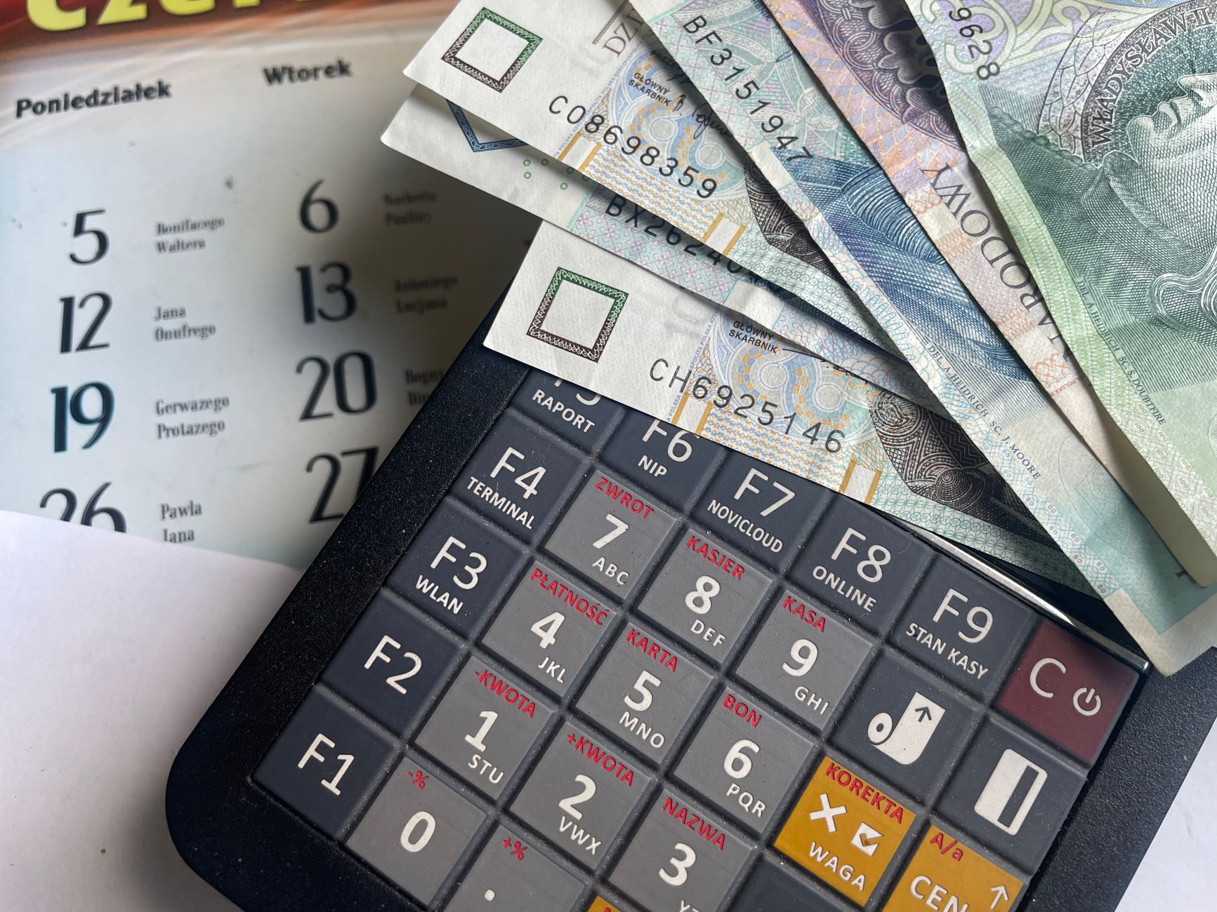 Banknoty złotówek na kalkulatorze, w tle kalendarz