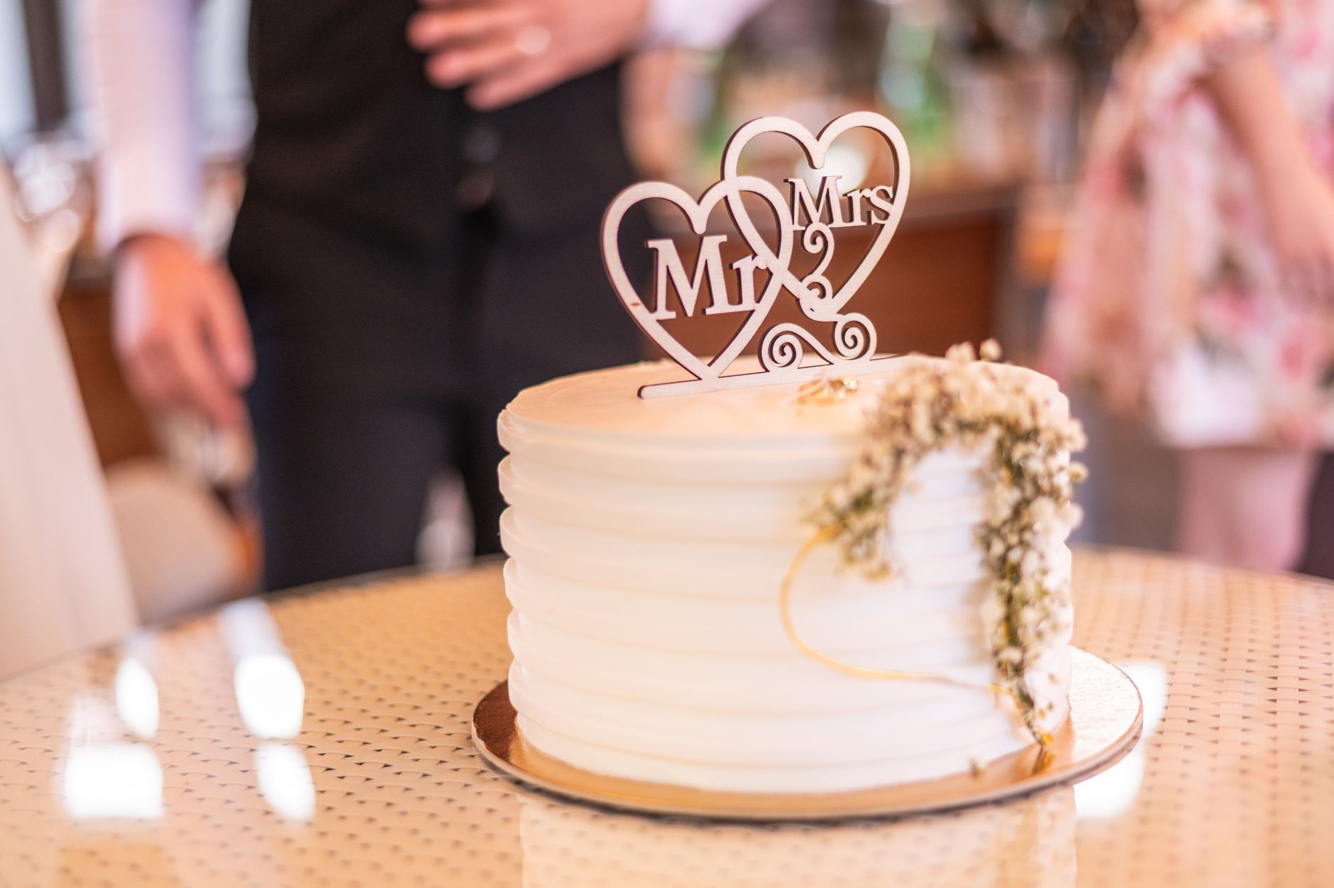 Biały tort weselny z napisem Mr & Mrs i kwiatowymi dekoracjami