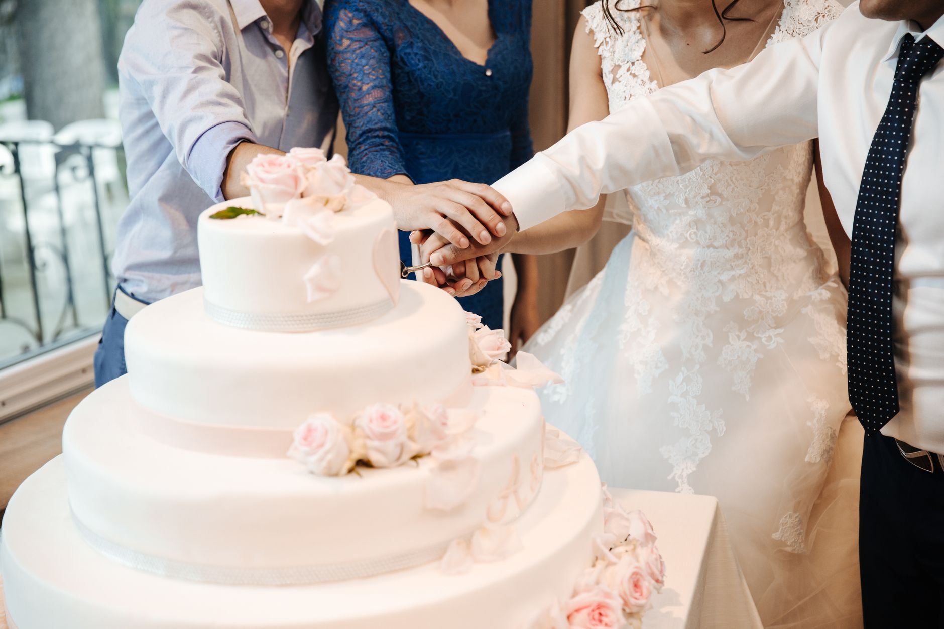 Para młoda kroi elegancki tort weselny w gronie rodziny i znajomych
