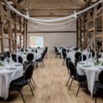Rustykalna sala weselna z elegancko nakrytymi okrągłymi stołami